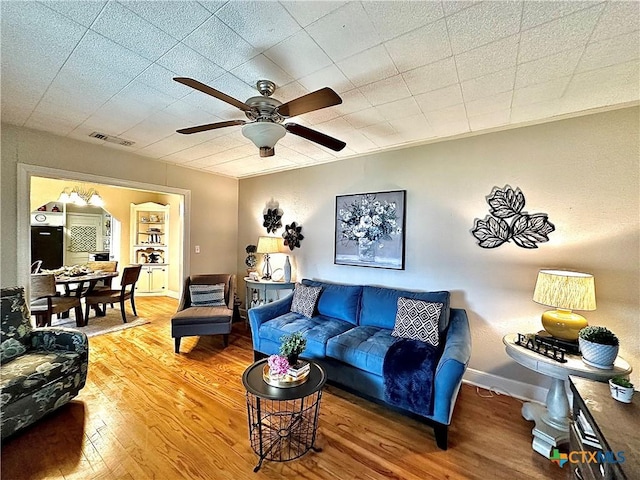 living area with baseboards, ceiling fan, visible vents, and wood finished floors