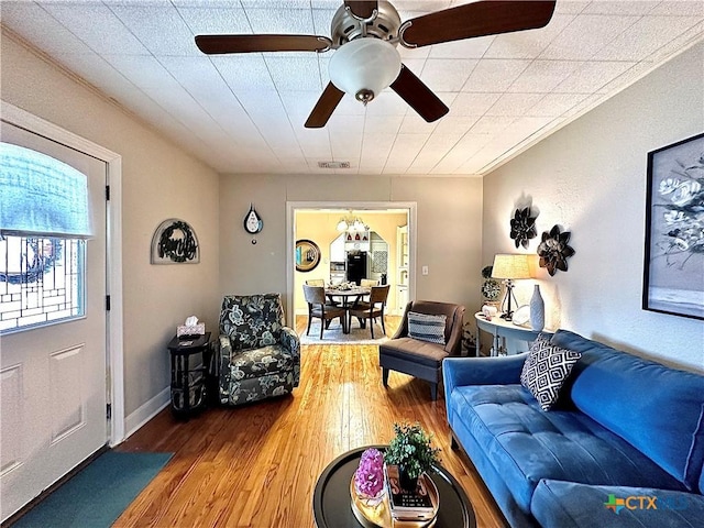 living room with a ceiling fan, baseboards, visible vents, and wood finished floors