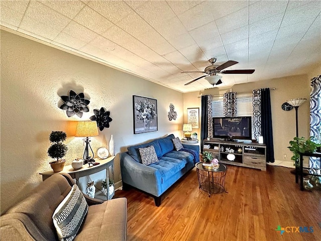 living area featuring ceiling fan, baseboards, wood finished floors, and a textured wall