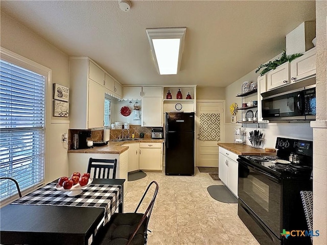 kitchen featuring open shelves, a sink, white cabinetry, decorative backsplash, and black appliances