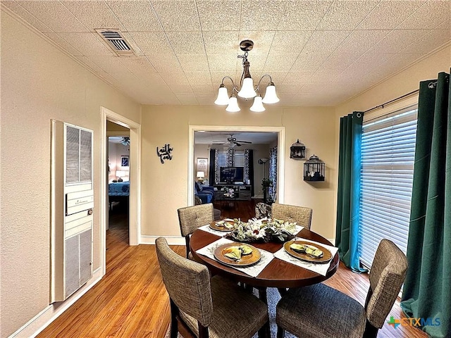 dining room featuring baseboards, ceiling fan with notable chandelier, visible vents, and light wood-style floors