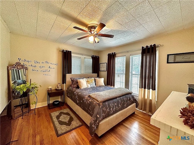 bedroom with ceiling fan, baseboards, and wood finished floors