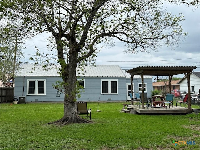 back of house featuring a deck, fence, metal roof, and a yard