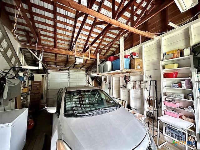 garage with a garage door opener, wooden walls, and refrigerator