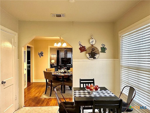 dining area with visible vents, a notable chandelier, and wood finished floors