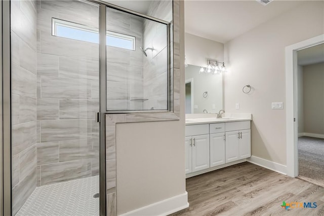 bathroom featuring walk in shower, vanity, and wood-type flooring