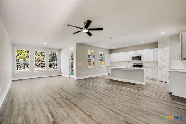 unfurnished living room with ceiling fan, sink, and light hardwood / wood-style flooring