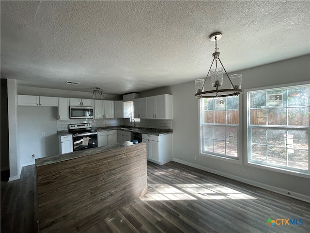 kitchen with hanging light fixtures, dark hardwood / wood-style flooring, a notable chandelier, white cabinets, and appliances with stainless steel finishes