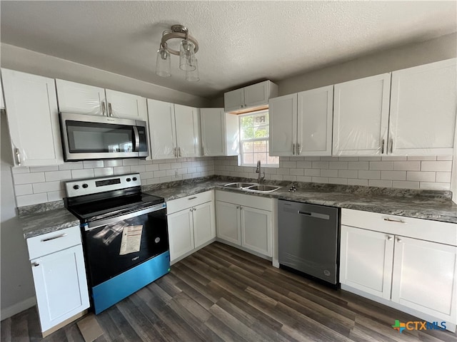 kitchen featuring appliances with stainless steel finishes, a textured ceiling, dark wood-type flooring, sink, and white cabinets