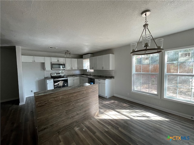 kitchen featuring decorative light fixtures, white cabinetry, stainless steel appliances, and dark wood-type flooring