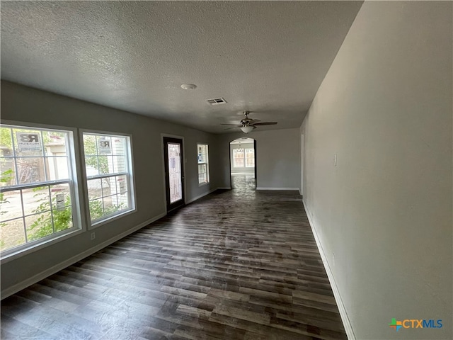 empty room with ceiling fan, dark wood-type flooring, and a textured ceiling