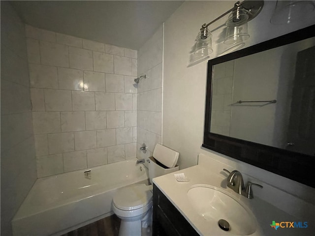 full bathroom featuring vanity, tiled shower / bath combo, and toilet