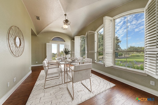 dining space with dark wood-type flooring and vaulted ceiling