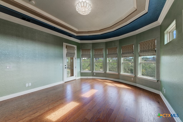 spare room with ornamental molding, plenty of natural light, wood-type flooring, and a notable chandelier