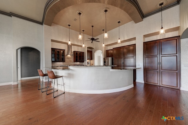 kitchen featuring hanging light fixtures, dark hardwood / wood-style flooring, stainless steel fridge with ice dispenser, and high vaulted ceiling