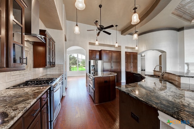 kitchen with sink, high vaulted ceiling, dark hardwood / wood-style floors, appliances with stainless steel finishes, and dark stone countertops