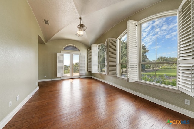 spare room featuring dark wood-type flooring, vaulted ceiling, and french doors