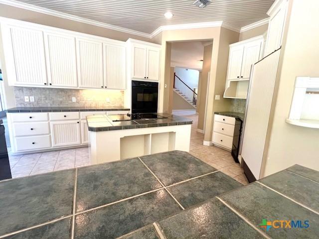 kitchen with backsplash, light tile patterned flooring, black electric cooktop, and tile counters