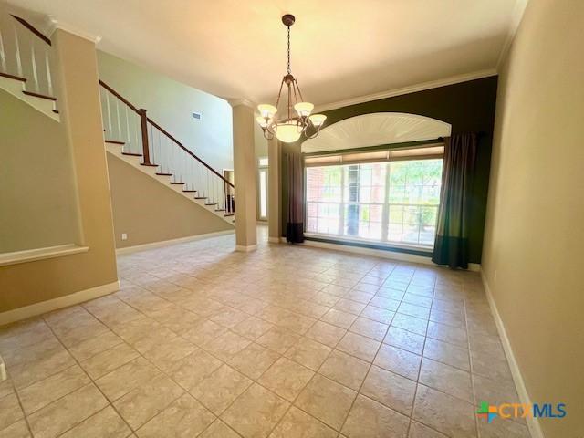 unfurnished room with crown molding, a chandelier, light tile patterned flooring, stairs, and baseboards