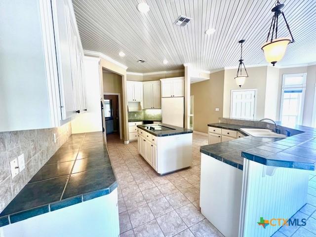 kitchen featuring tasteful backsplash, light tile patterned floors, a large island, a sink, and wood ceiling