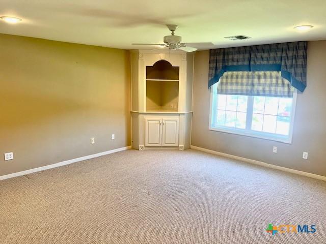 empty room featuring visible vents, baseboards, light colored carpet, and ceiling fan
