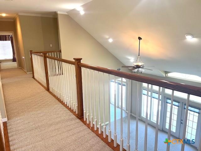 hall with lofted ceiling, carpet, crown molding, and a healthy amount of sunlight