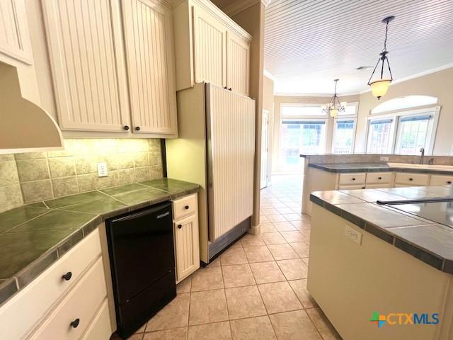 kitchen with light tile patterned floors, crown molding, black dishwasher, decorative backsplash, and fridge