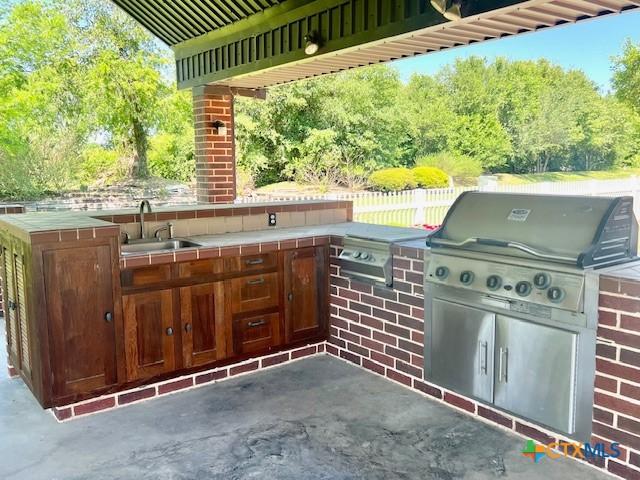 view of patio / terrace with a sink, fence, exterior kitchen, and area for grilling