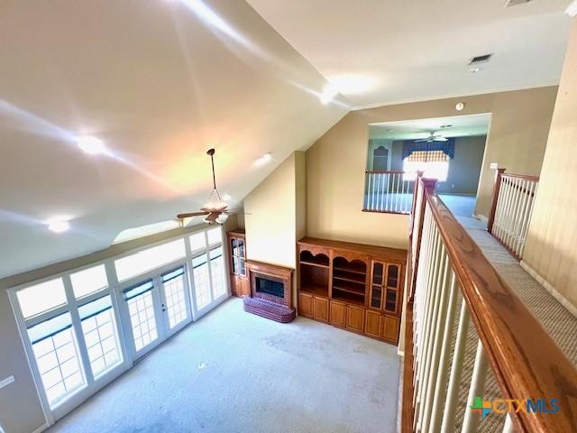 additional living space with a fireplace, lofted ceiling, a ceiling fan, and carpet floors