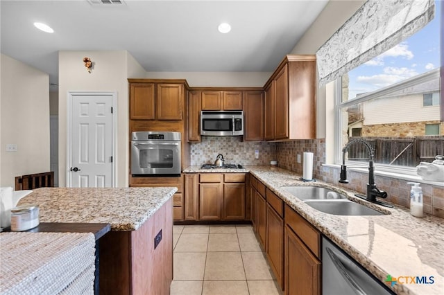 1901 Deer Field Way, Harker Heights, TX 76548 - kitchen featuring stainless steel appliances, brown cabinetry, tasteful backsplash, light stone countertops, and recessed lighting