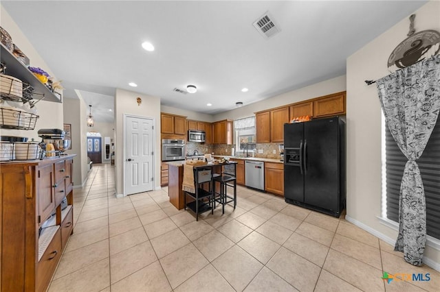1901 Deer Field Way, Harker Heights, TX 76548 - kitchen featuring stainless steel appliances, brown cabinets, a kitchen breakfast bar, backsplash, and a center island