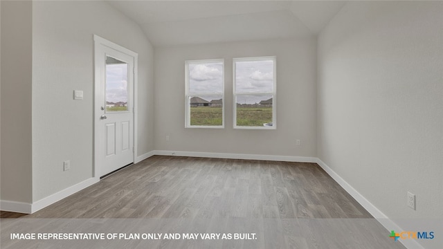 empty room featuring light hardwood / wood-style floors and vaulted ceiling