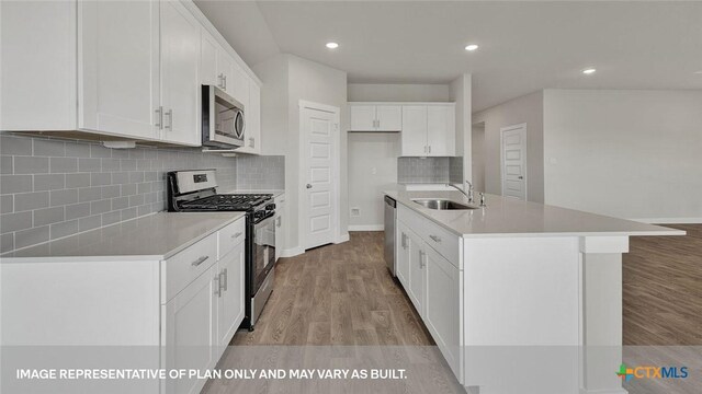 575 Radley Rd, Lockhart, TX 78644 - kitchen featuring appliances with stainless steel finishes, a sink, light wood finished floors, white cabinets, and recessed lighting