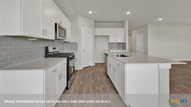 kitchen featuring a kitchen island with sink, sink, white cabinets, and stainless steel appliances