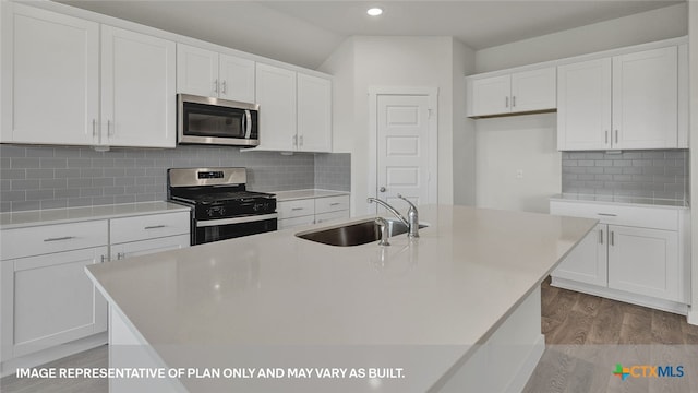 kitchen featuring stainless steel appliances, a kitchen island with sink, sink, white cabinets, and light hardwood / wood-style floors