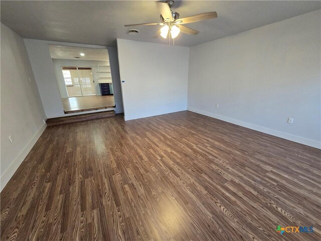 unfurnished room with ceiling fan, built in features, and dark hardwood / wood-style floors