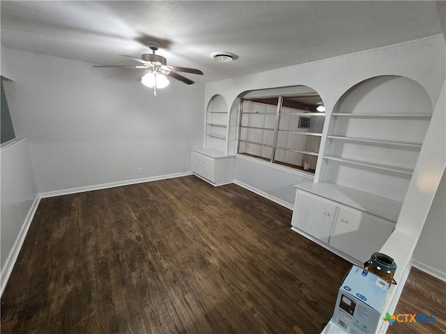 empty room with ceiling fan, built in features, and dark hardwood / wood-style floors