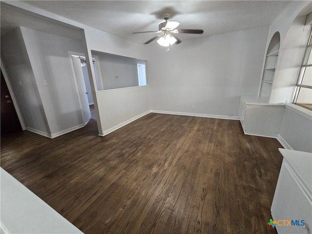 empty room featuring dark wood finished floors, baseboards, and ceiling fan