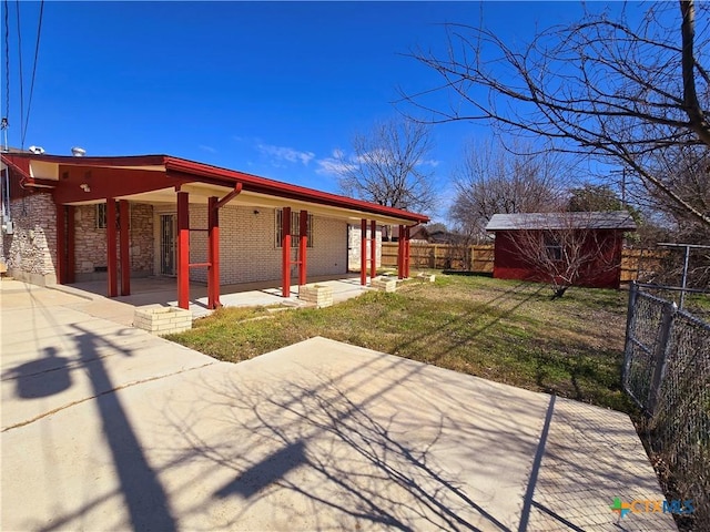 exterior space featuring stone siding, fence, a yard, an outdoor structure, and brick siding