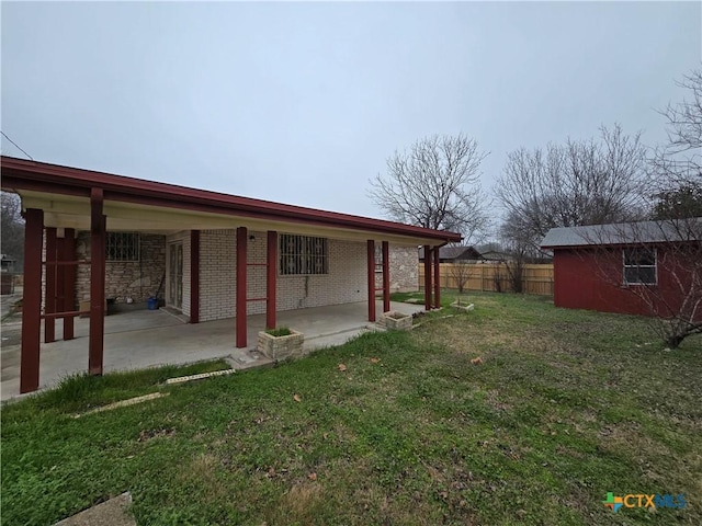 view of yard with fence, an outbuilding, and a patio