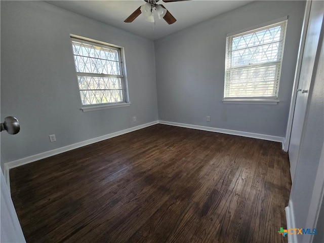 spare room with ceiling fan, dark wood-type flooring, and baseboards