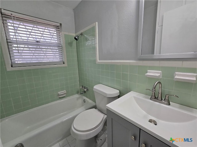 full bathroom with tile walls, toilet, vanity, and tiled shower / bath