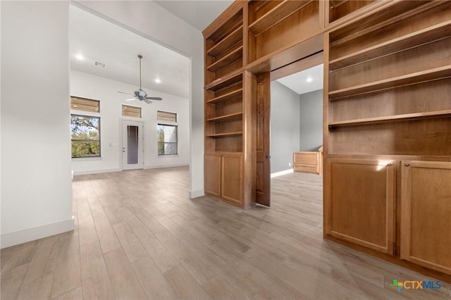 interior space with ceiling fan, built in features, and light hardwood / wood-style floors