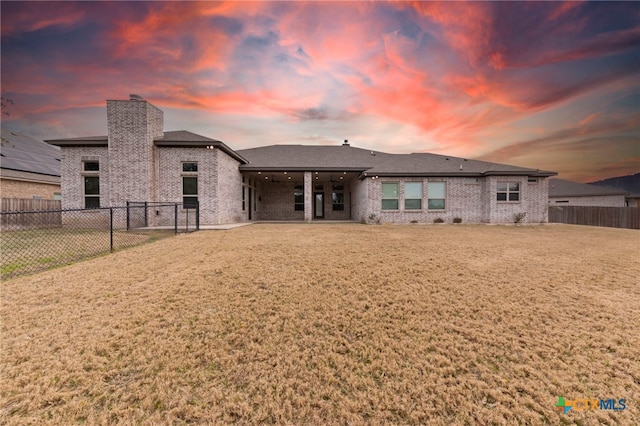 back house at dusk with a lawn