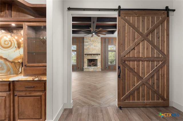 interior space featuring parquet floors, beamed ceiling, and a barn door