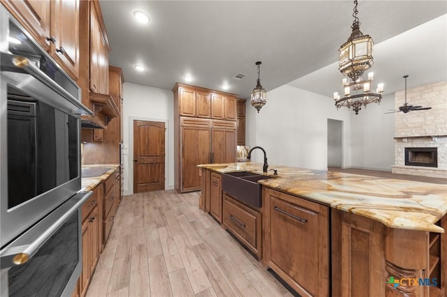 kitchen featuring hanging light fixtures, sink, a stone fireplace, and oven