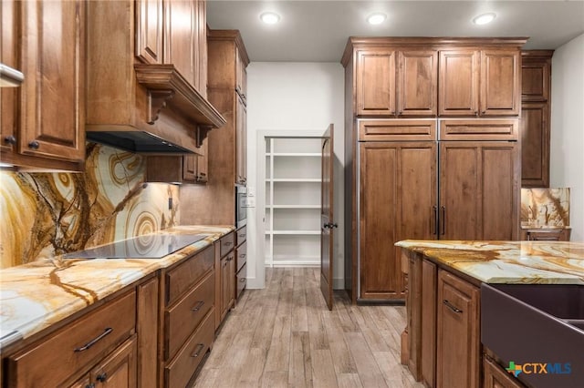 kitchen with light stone counters, black electric stovetop, light hardwood / wood-style flooring, and tasteful backsplash