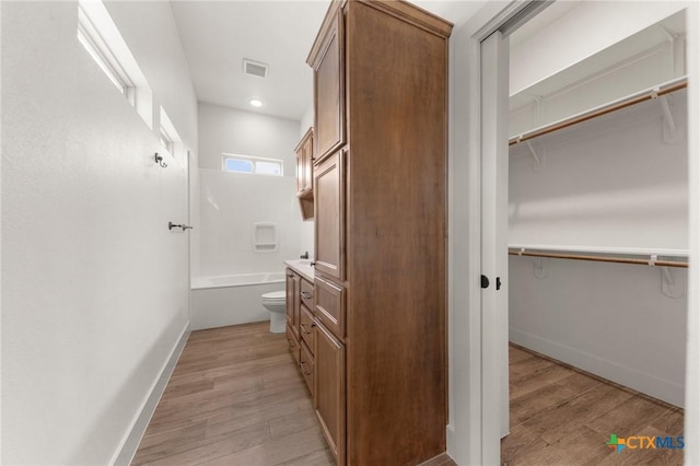 full bathroom featuring toilet, vanity,  shower combination, and hardwood / wood-style floors