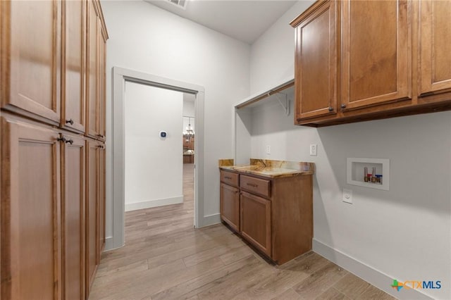 laundry room featuring light wood-type flooring, hookup for a washing machine, and cabinets