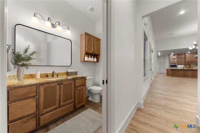 bathroom featuring toilet, vanity, a chandelier, and hardwood / wood-style floors